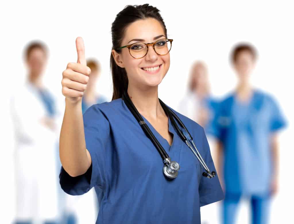 Nurse portrait full length giving thumbs up in front of a medical team