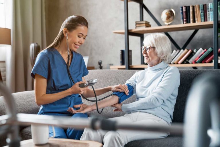 Nurse measuring blood pressure of elderly woman indoors